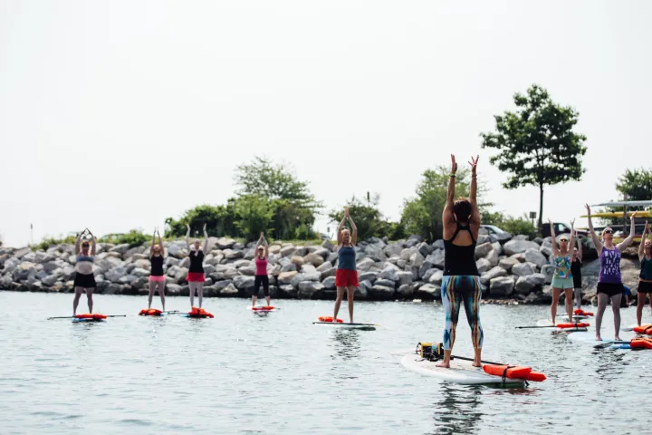a group of people follow an instructor's lead as they do yoga on paddleboards
