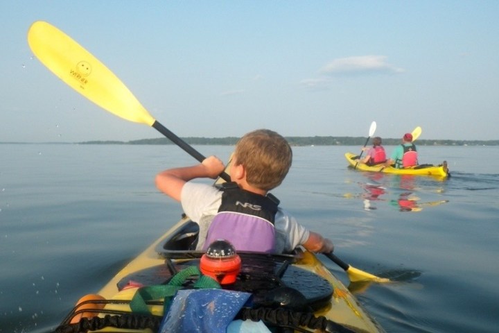 a young boy sitting on a boat in the water