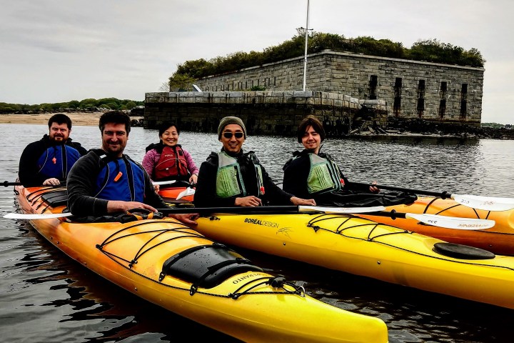 a group of people riding on the back of a boat in the water