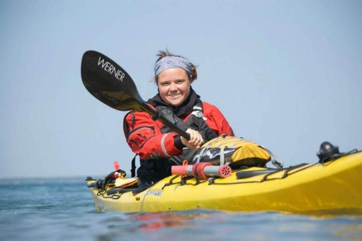 Person in red jacket kayaking on calm water with a yellow kayak.