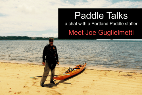 a man standing on a beach holding a surf board in the water