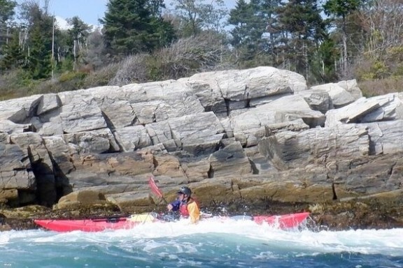 a group of people on a rock next to water