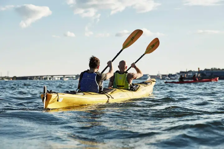 Two guys paddling a tandem kayak in Portland, Maine