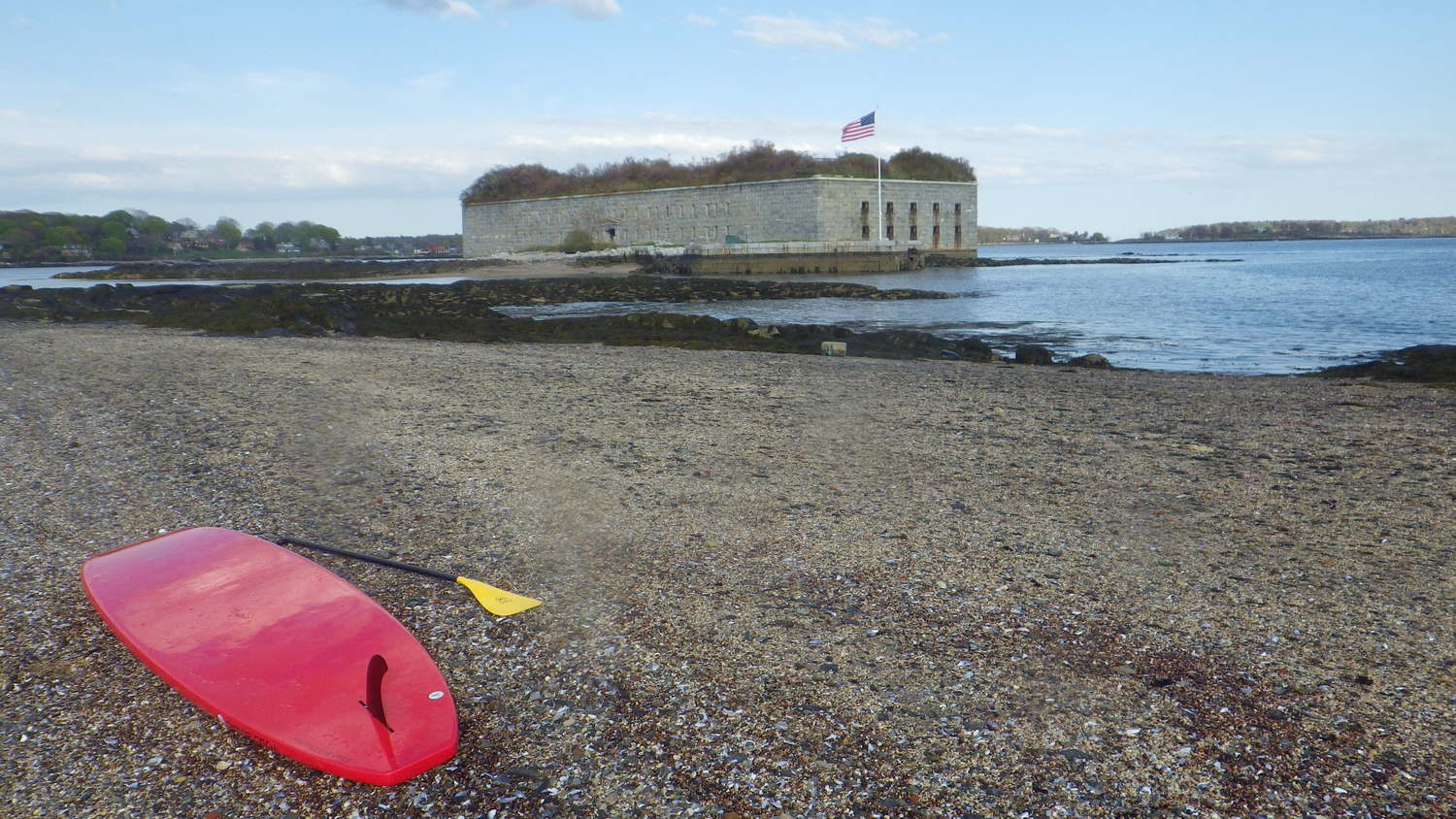 a beach with a surf board on a body of water