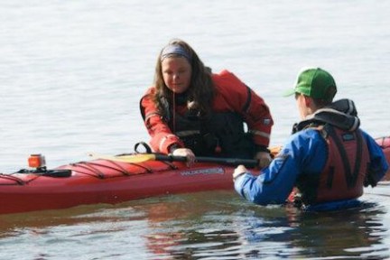 An instructor teaching a student how to roll a kayak