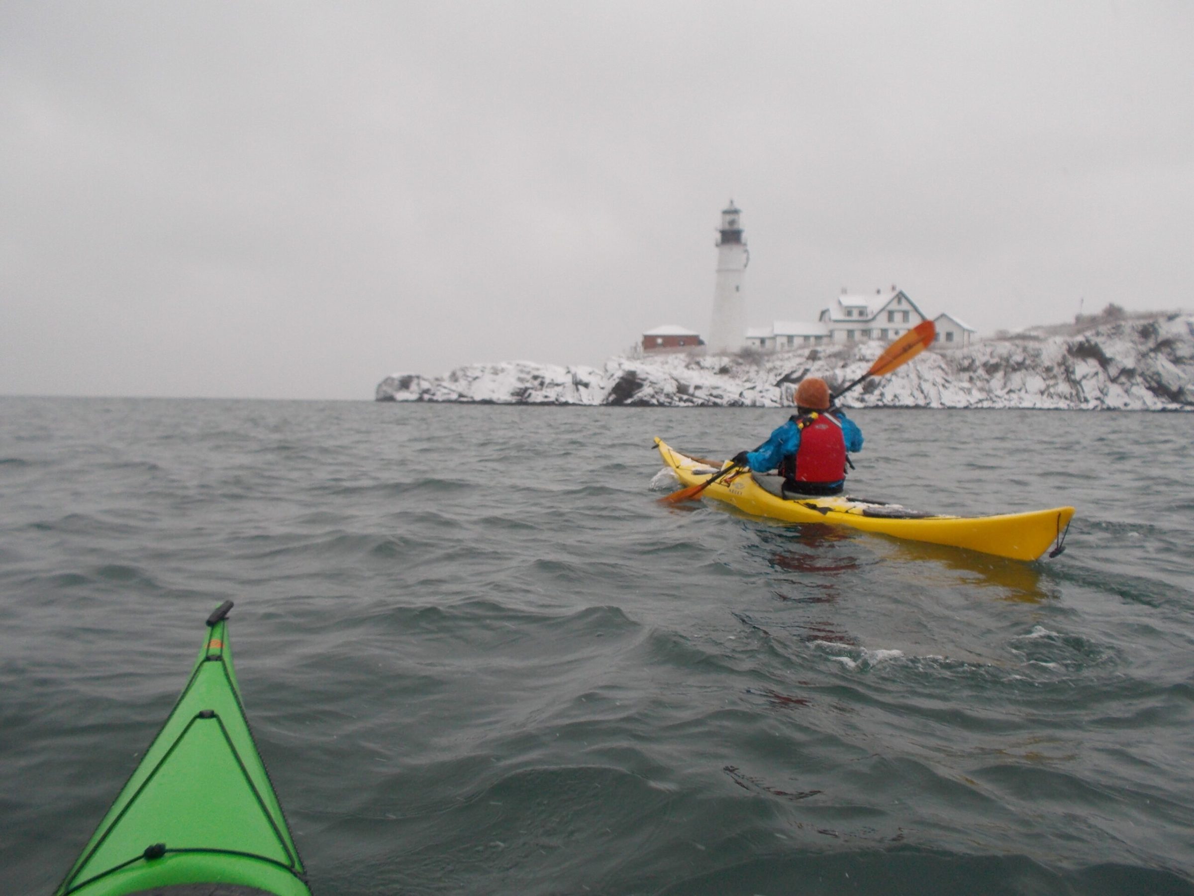 Paddlers in winter pass Portland Headlight