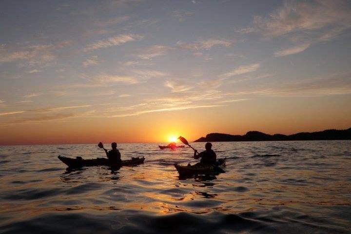 a group of people on a beach with a sunset in the background