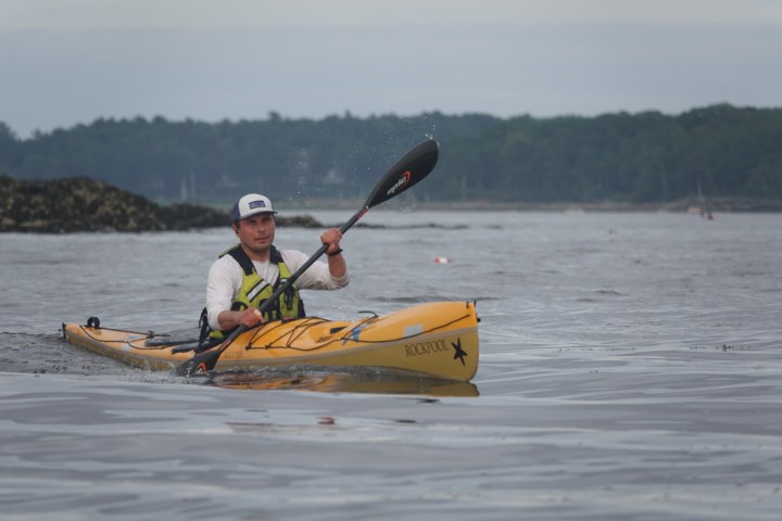 a man riding on the back of a boat on a body of water