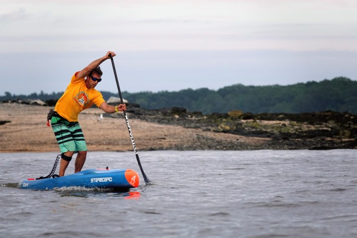 a man riding on the back of a boat in a body of water