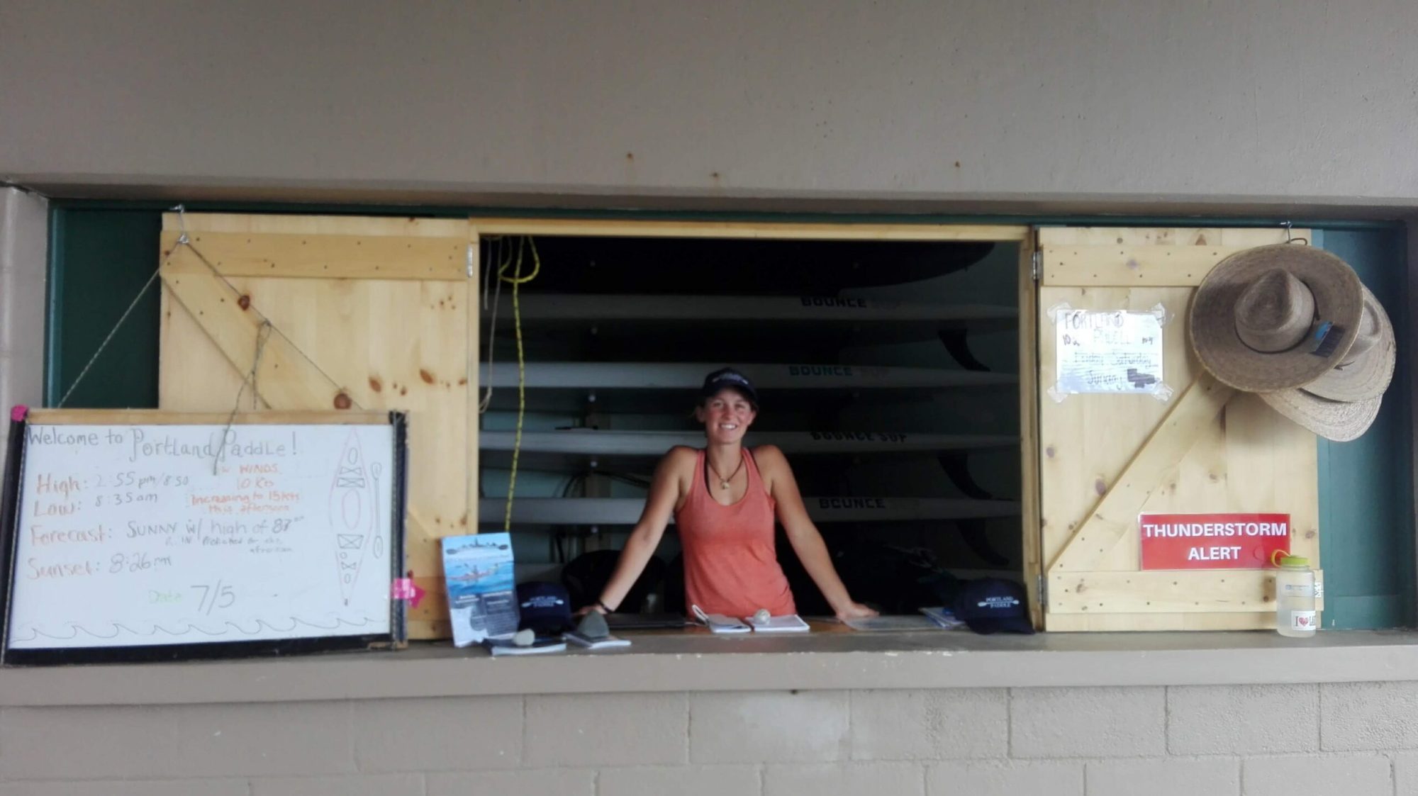 A person at the front desk of a kayak shop on the beach