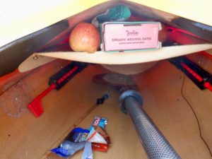 Fruits and granola bars stuffed inside a shelf in a kayak's cockpit
