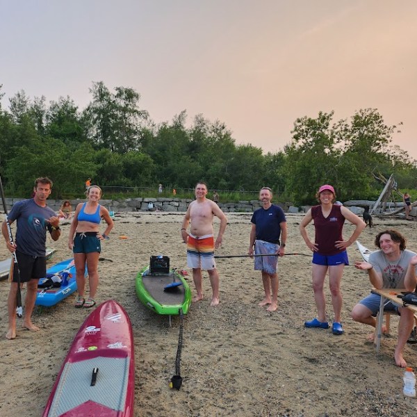 a group of people on a beach with paddleboards