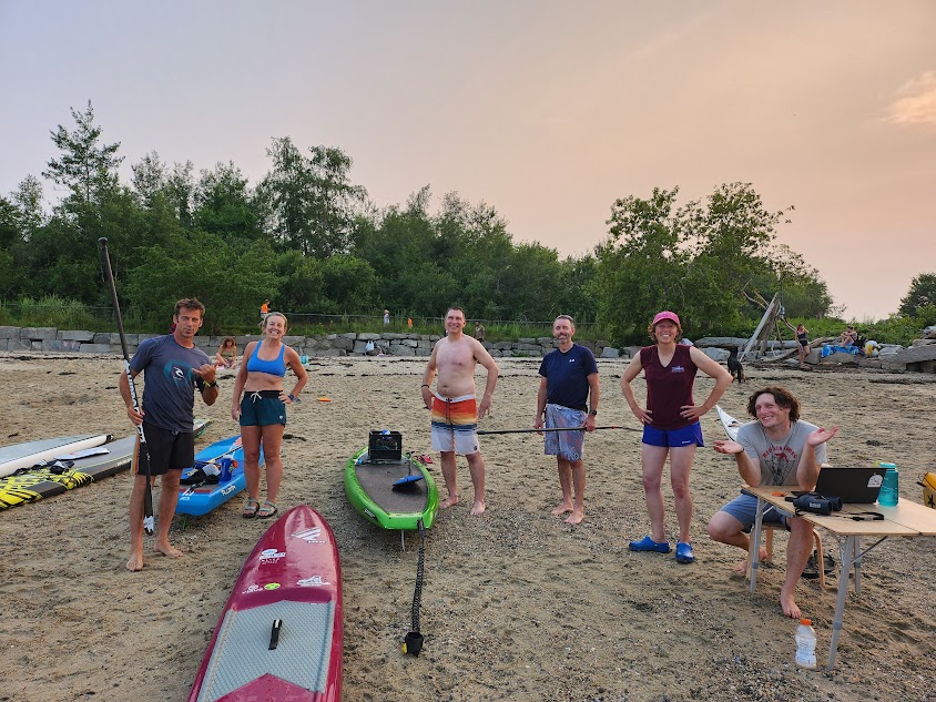 a group of people on a beach with paddleboards