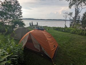 a tent in a grassy area next to a body of water