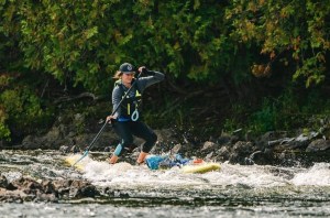 A woman on a paddleboard in a bumpy river