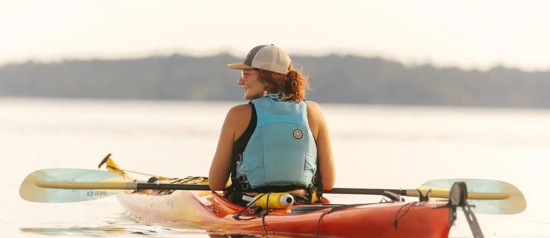 a woman sitting in a sea kayak at sunset