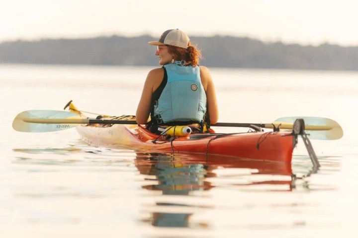a woman sitting in a sea kayak at sunset