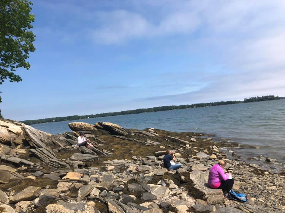 Writing students practice their craft on a rocky beach on the coast of Maine
